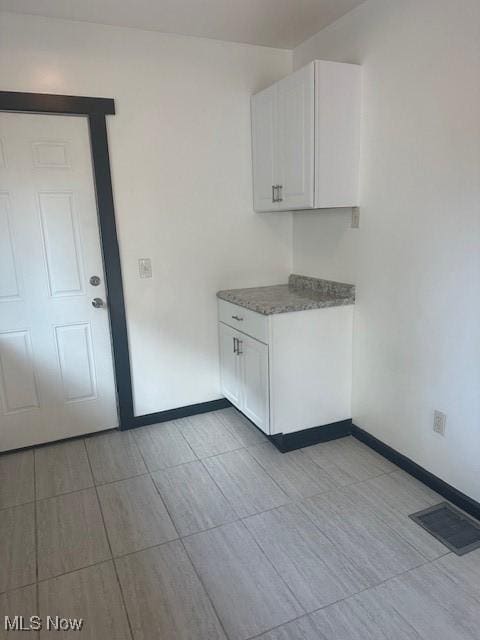 kitchen featuring white cabinets, baseboards, and visible vents