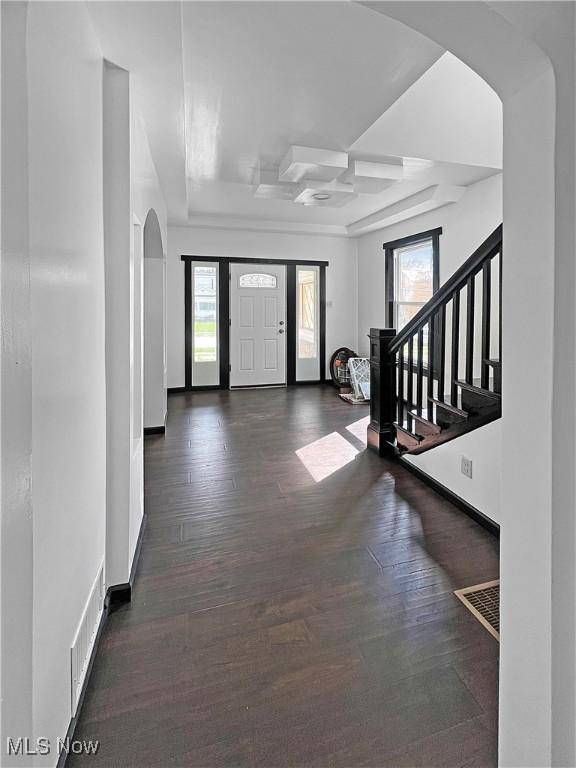 foyer entrance featuring stairway, arched walkways, wood finished floors, and plenty of natural light