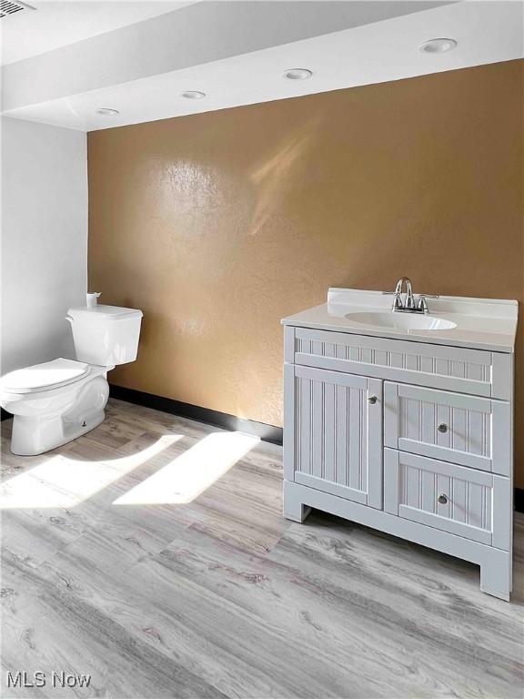 bathroom with wood finished floors, recessed lighting, vanity, and toilet