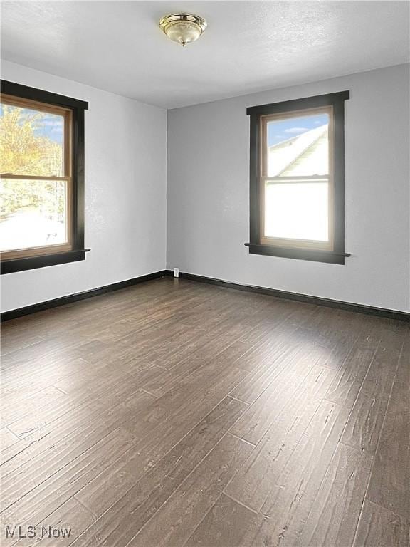 empty room featuring baseboards and dark wood-style flooring
