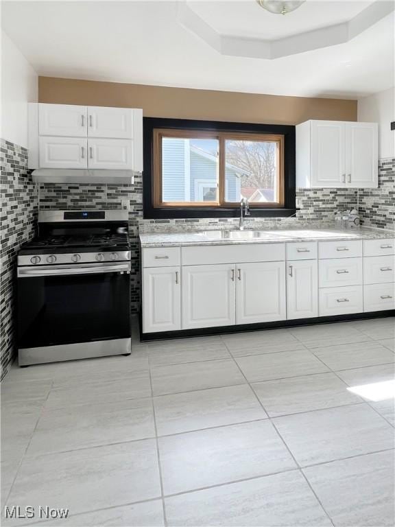 kitchen featuring white cabinets, a sink, light tile patterned flooring, backsplash, and stainless steel gas stove