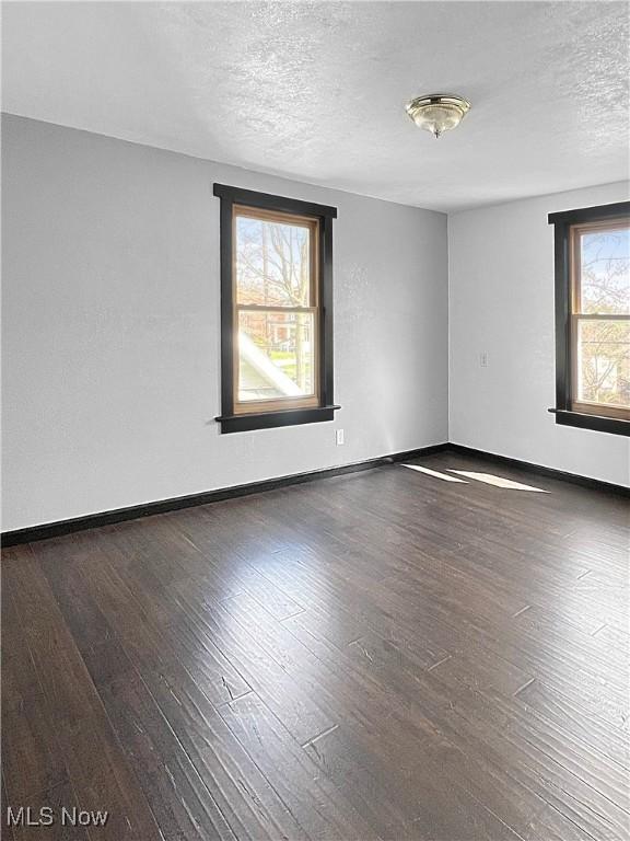 spare room with baseboards, wood finished floors, and a textured ceiling
