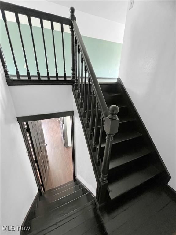 staircase featuring a towering ceiling and wood finished floors
