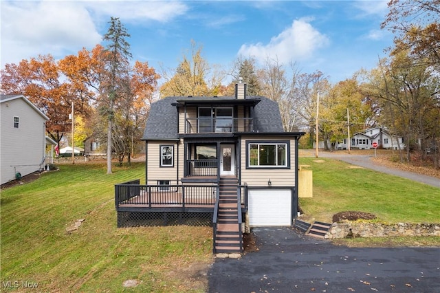 view of front of property with a balcony, driveway, an attached garage, a chimney, and a front lawn