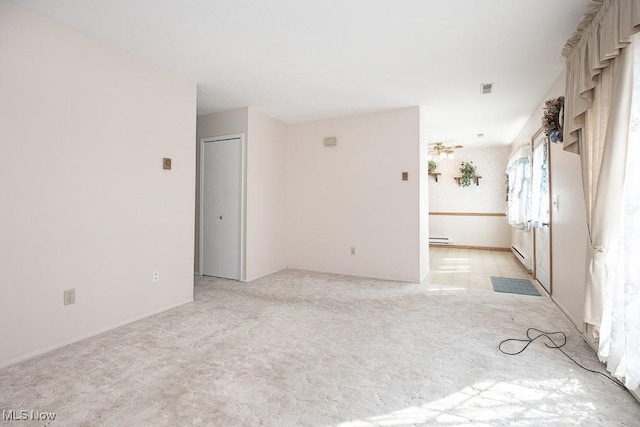 spare room featuring a baseboard heating unit, light carpet, baseboard heating, and visible vents