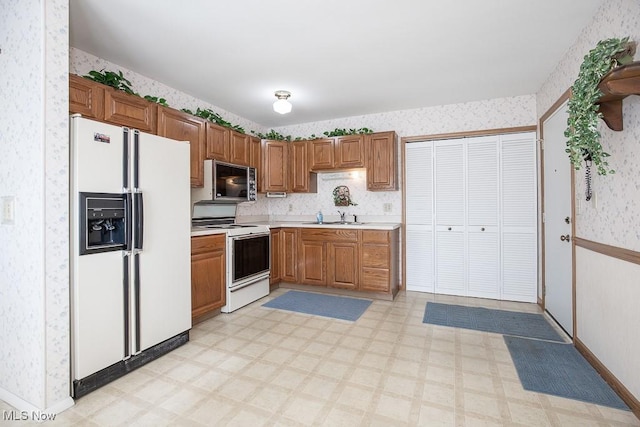 kitchen featuring white appliances, light floors, and wallpapered walls