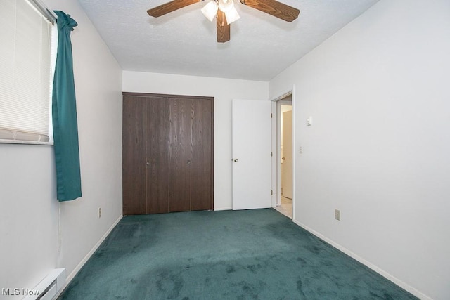 unfurnished bedroom featuring ceiling fan, carpet floors, baseboard heating, a closet, and a textured ceiling