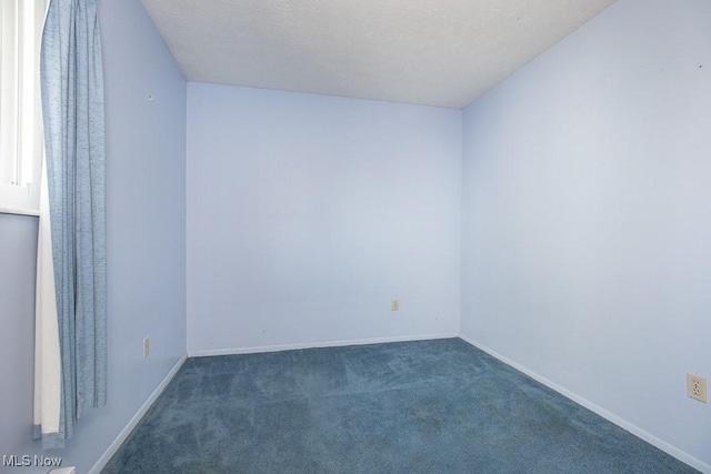 unfurnished room with baseboards, a textured ceiling, and dark carpet