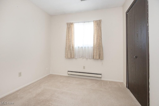 carpeted empty room with a baseboard radiator and baseboards