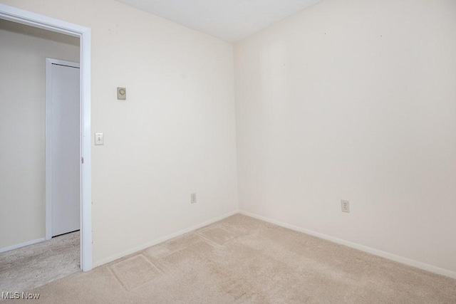 spare room featuring light carpet and baseboards