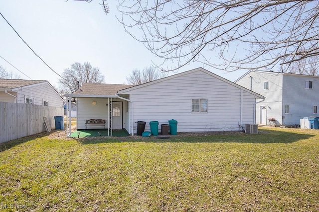 rear view of property featuring a lawn, fence, central AC, and roof with shingles