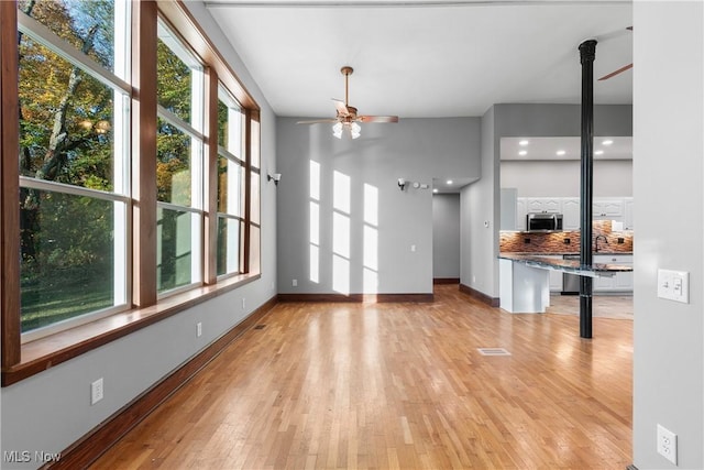 unfurnished living room with baseboards, visible vents, a ceiling fan, and light wood-style floors