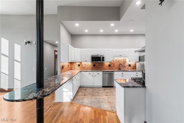 kitchen with tasteful backsplash, dark stone countertops, appliances with stainless steel finishes, and white cabinetry