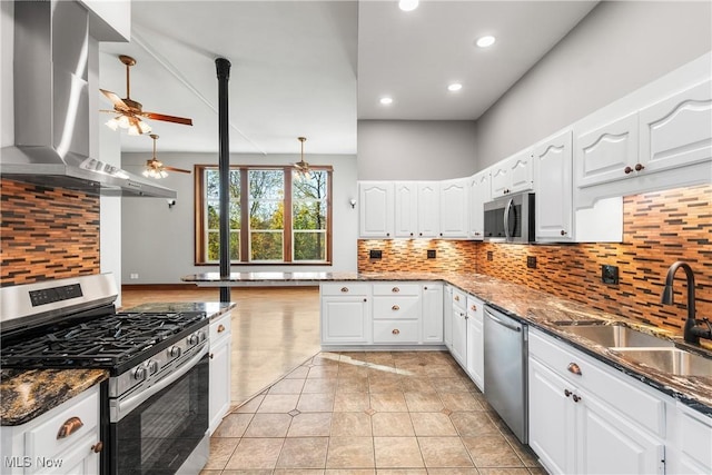 kitchen featuring white cabinets, wall chimney exhaust hood, appliances with stainless steel finishes, and a sink