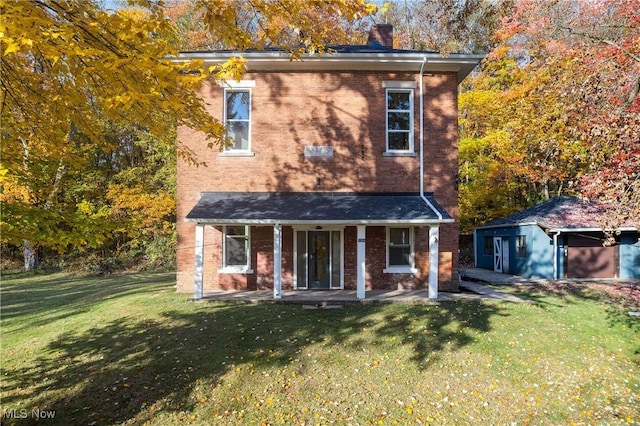 view of front of home with a front lawn, an outbuilding, brick siding, and a chimney