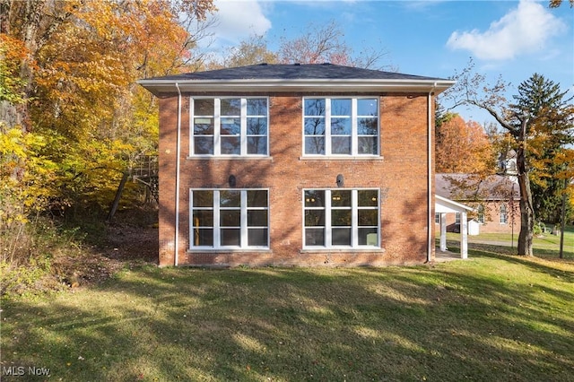 rear view of house featuring brick siding and a lawn