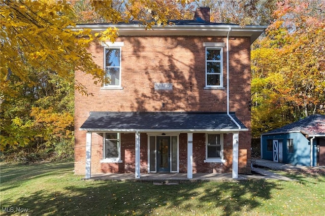 view of front of house with brick siding, a chimney, and a front yard