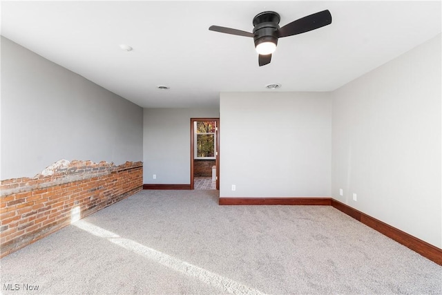 carpeted empty room with visible vents, baseboards, and ceiling fan