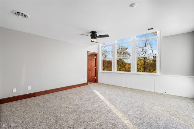 carpeted empty room featuring visible vents and a ceiling fan