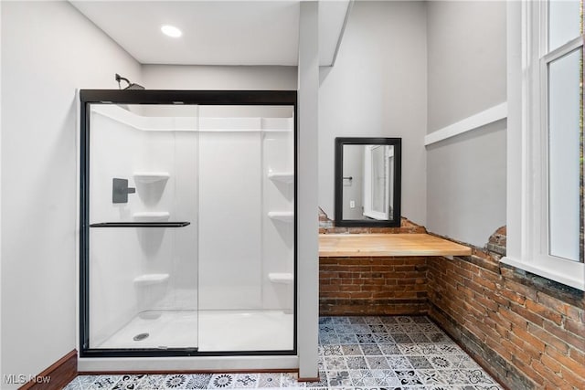 full bathroom featuring a shower stall and brick wall