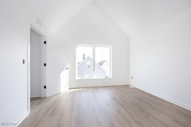 additional living space with light wood finished floors, visible vents, high vaulted ceiling, and baseboards