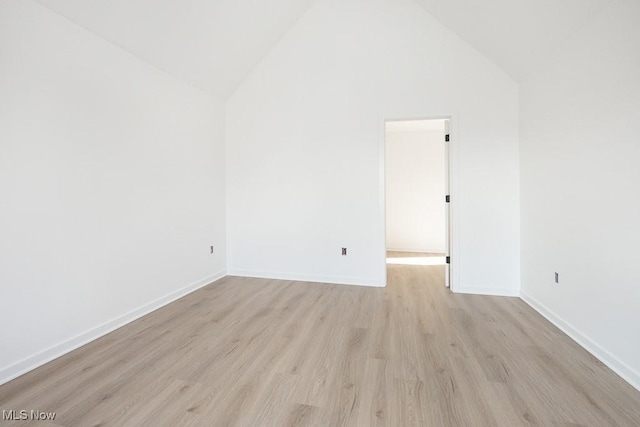 unfurnished room with light wood-style floors, baseboards, and high vaulted ceiling