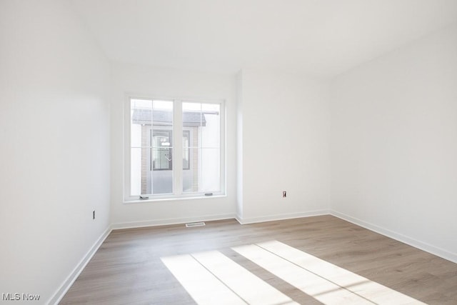 unfurnished room featuring light wood-style flooring, baseboards, and visible vents