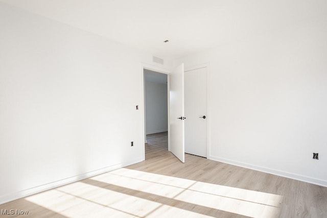 empty room with visible vents, light wood-style flooring, and baseboards