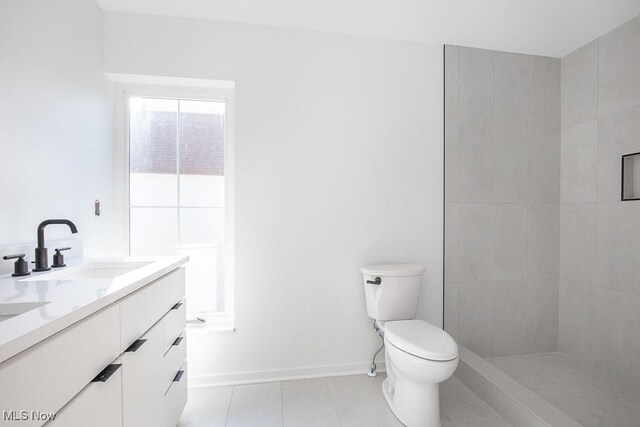 full bathroom featuring baseboards, toilet, tiled shower, tile patterned floors, and vanity