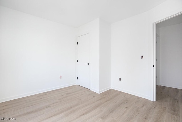 empty room featuring baseboards and light wood finished floors