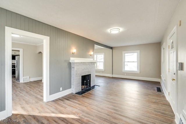 unfurnished living room with visible vents, a fireplace, baseboards, and wood finished floors