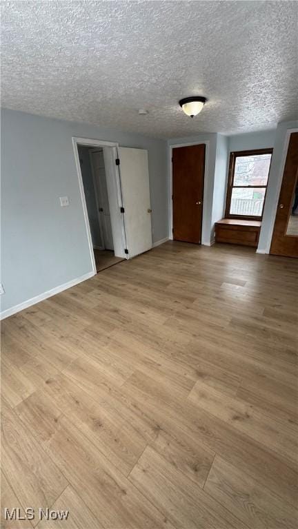 empty room featuring baseboards, a textured ceiling, and light wood finished floors