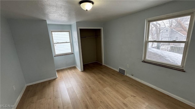 unfurnished bedroom featuring a closet, visible vents, baseboards, and light wood-style floors