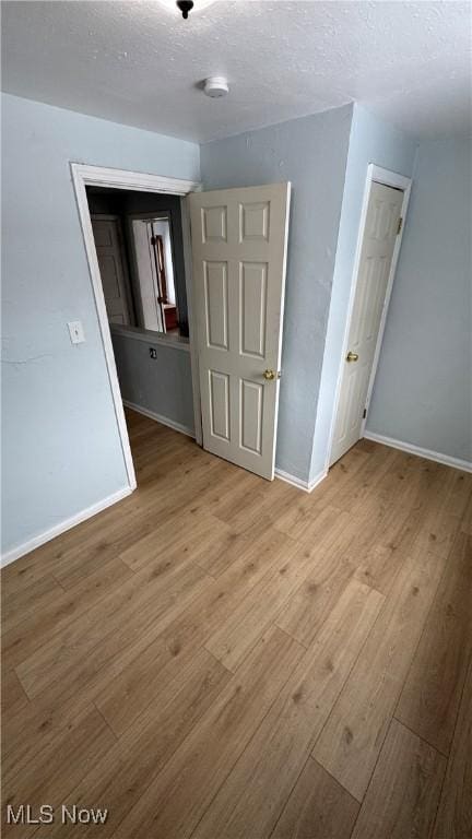 spare room featuring wood finished floors, baseboards, and a textured ceiling