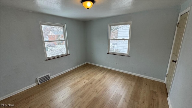 unfurnished bedroom featuring visible vents, multiple windows, baseboards, and light wood-style floors