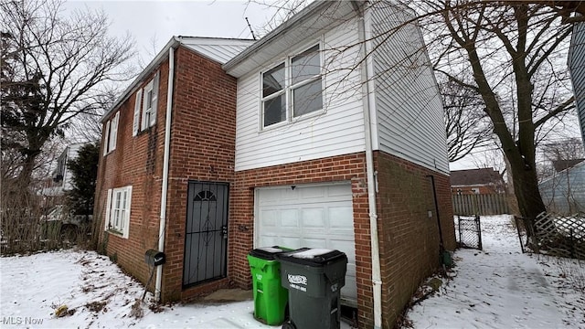 view of front facade featuring brick siding, a garage, and fence