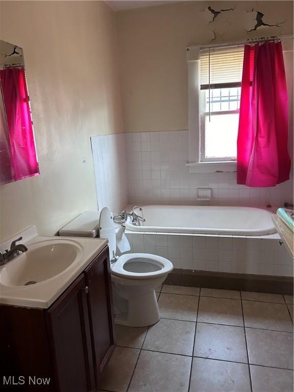 full bathroom featuring tile patterned flooring, toilet, vanity, and tiled bath