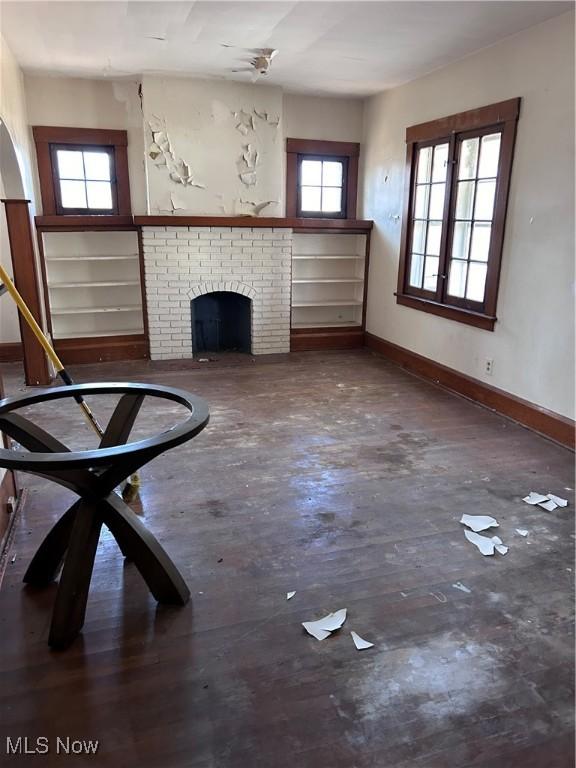 unfurnished living room with a fireplace, wood finished floors, and baseboards