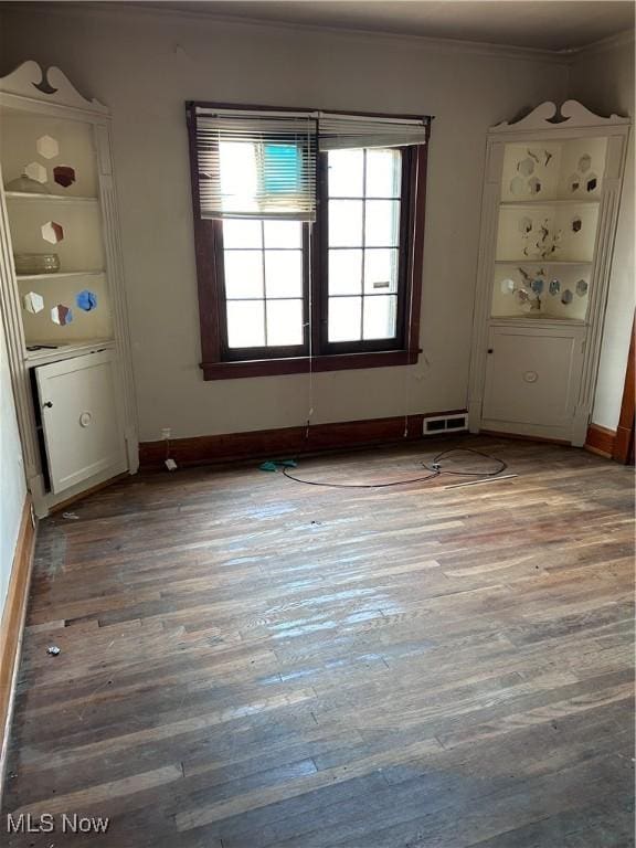 spare room with baseboards, visible vents, light wood finished floors, and ornamental molding