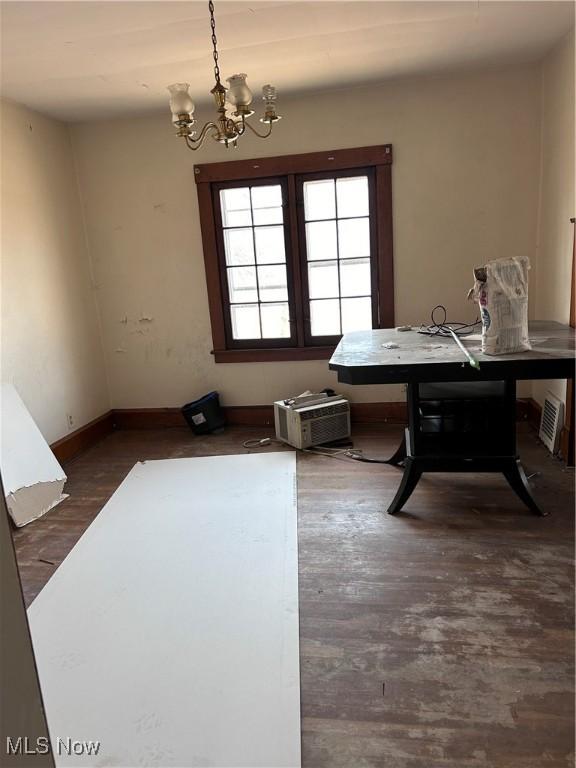 dining room with an AC wall unit, wood finished floors, baseboards, and a chandelier