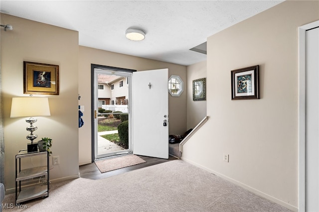 carpeted entrance foyer with a textured ceiling and baseboards