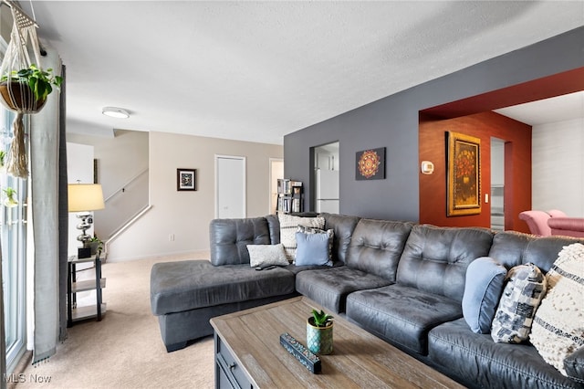 living room featuring an accent wall, a textured ceiling, baseboards, and light carpet