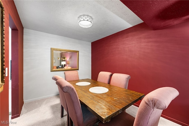 carpeted dining area with baseboards and a textured ceiling