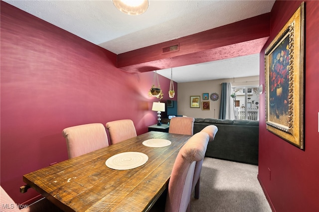 dining space with visible vents, carpet floors, a textured ceiling, and beamed ceiling