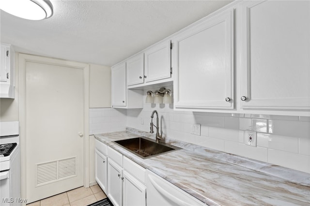 kitchen with white appliances, light tile patterned floors, a sink, white cabinets, and backsplash