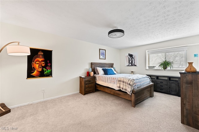 bedroom with light colored carpet, baseboards, and a textured ceiling