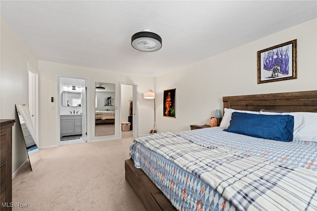 bedroom featuring light colored carpet, baseboards, ensuite bathroom, and a textured ceiling