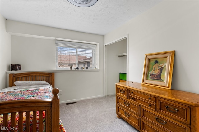 bedroom with visible vents, light colored carpet, a textured ceiling, and baseboards