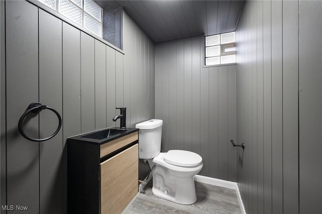 bathroom with toilet, vanity, baseboards, and wood finished floors