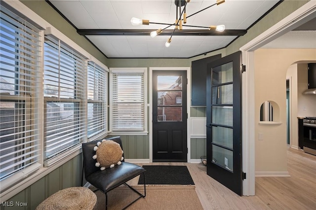 sunroom featuring arched walkways and a chandelier